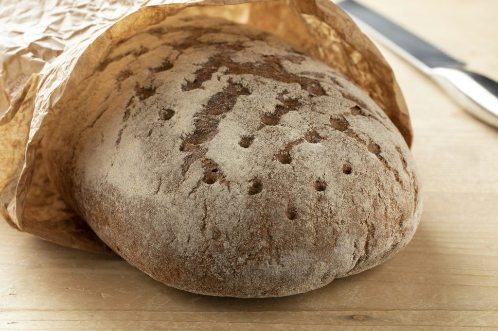 Whole German sourdough bread in a paper bag close up